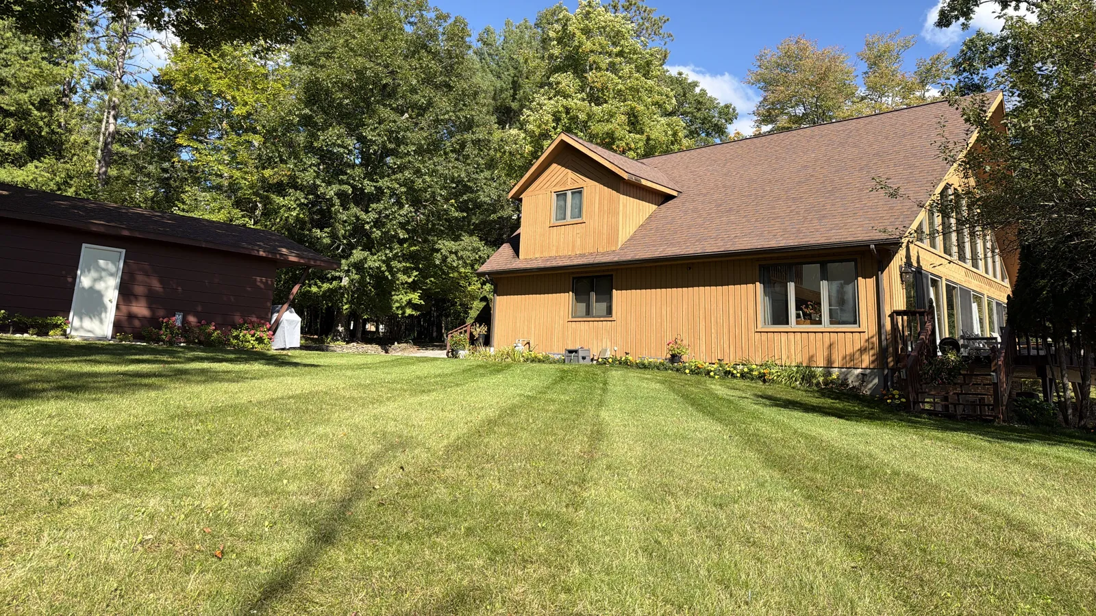A freshly striped lawn in front of a cedar-sided house on Hubbard Lake, mowed by Northern Michigan Lawn & Landscape
